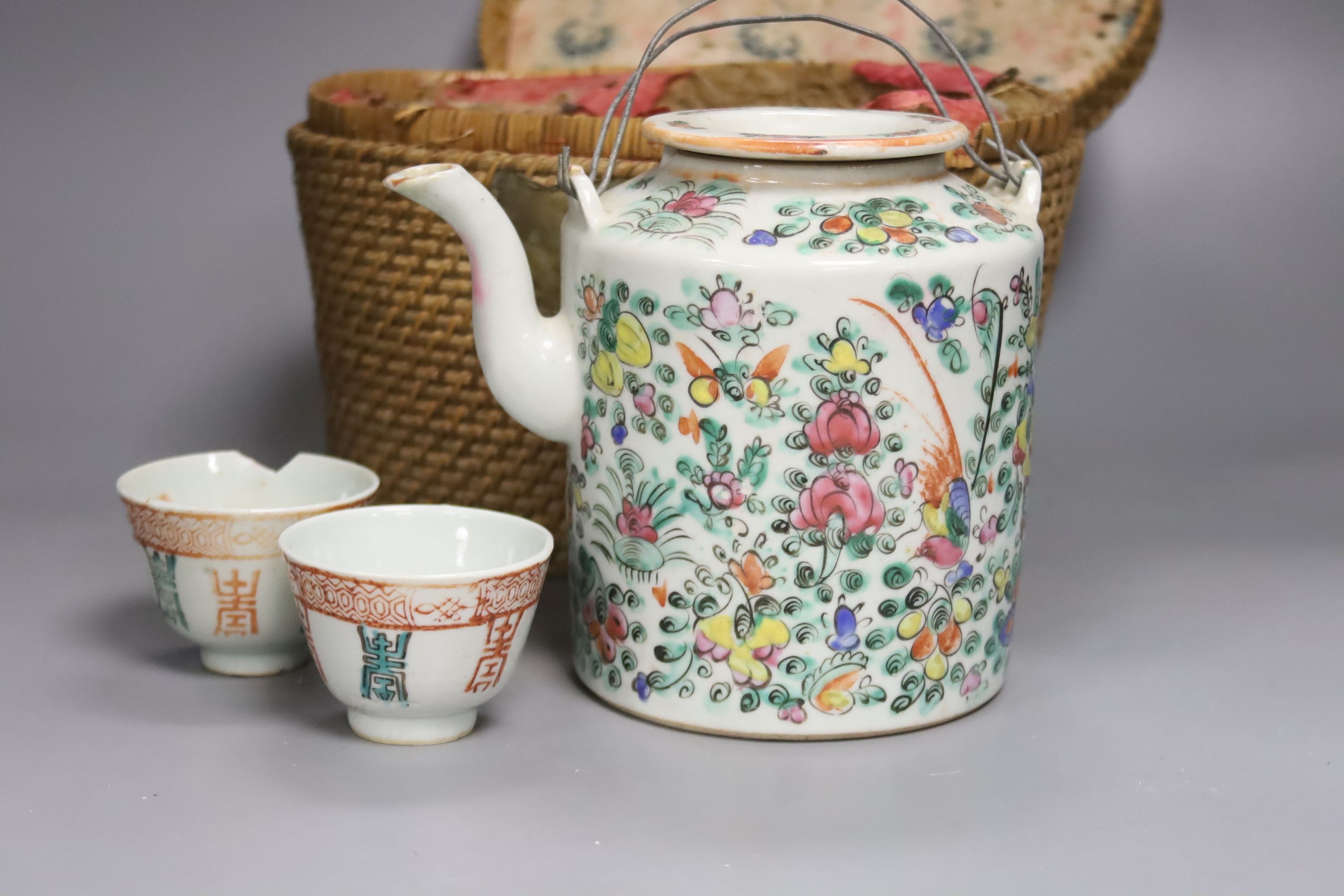 A Chinese teapot and two tea bowls, in carrying basket